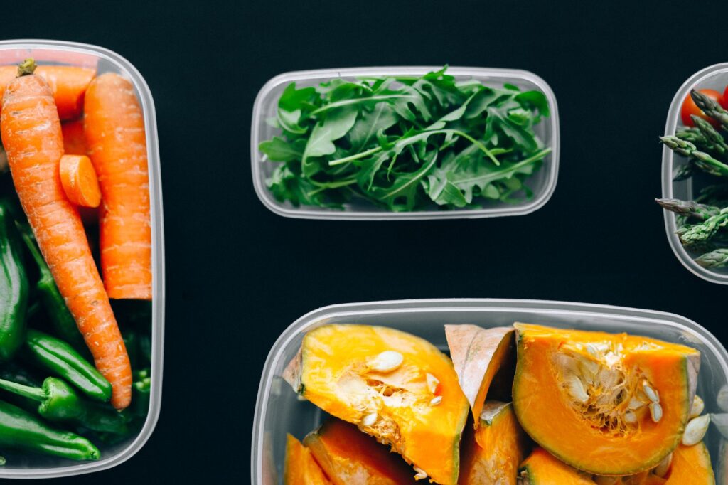 A row of glass containers filled with colorful vegan meal prep on a kitchen counter
