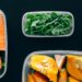 A row of glass containers filled with colorful vegan meal prep on a kitchen counter