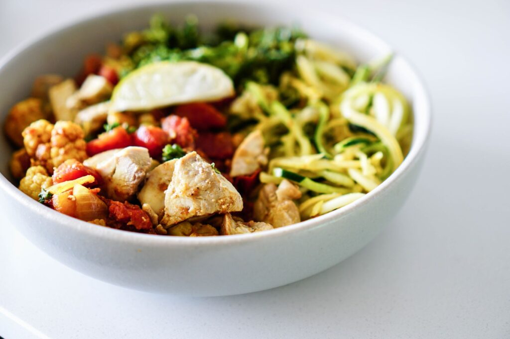 keto diet recipes prepped into a bowl with chicken, zucchini noodles and roasted vegetables