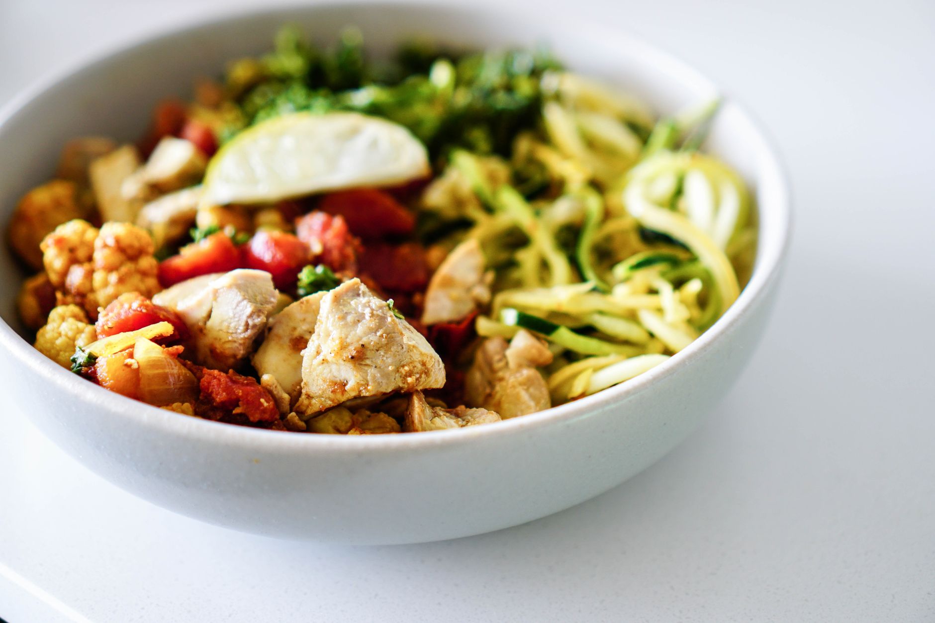 keto diet recipes prepped into a bowl with chicken, zucchini noodles and roasted vegetables